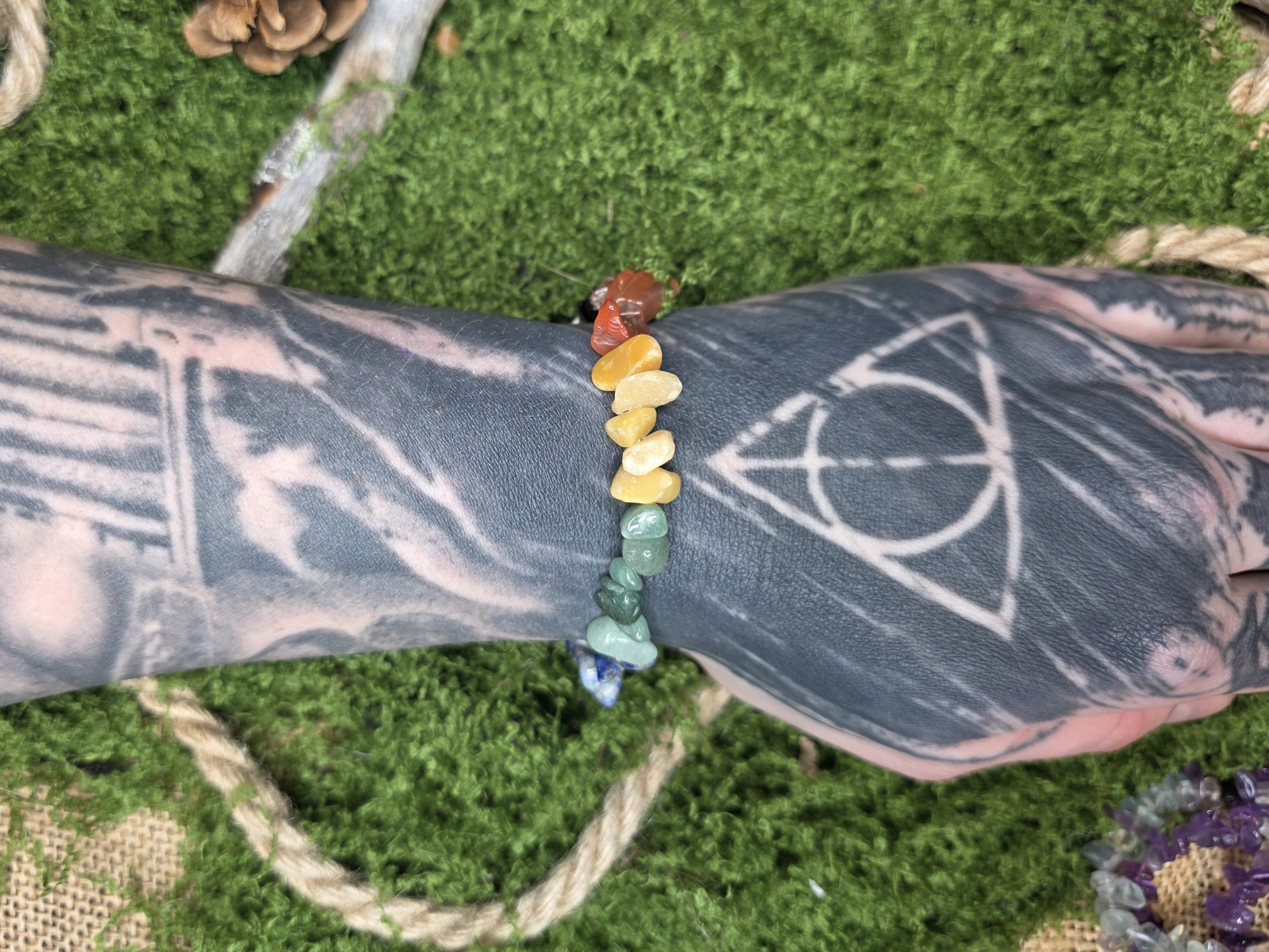 Eri värisistä kivisiruista valmistettu rannekoru mallin kädessä. 