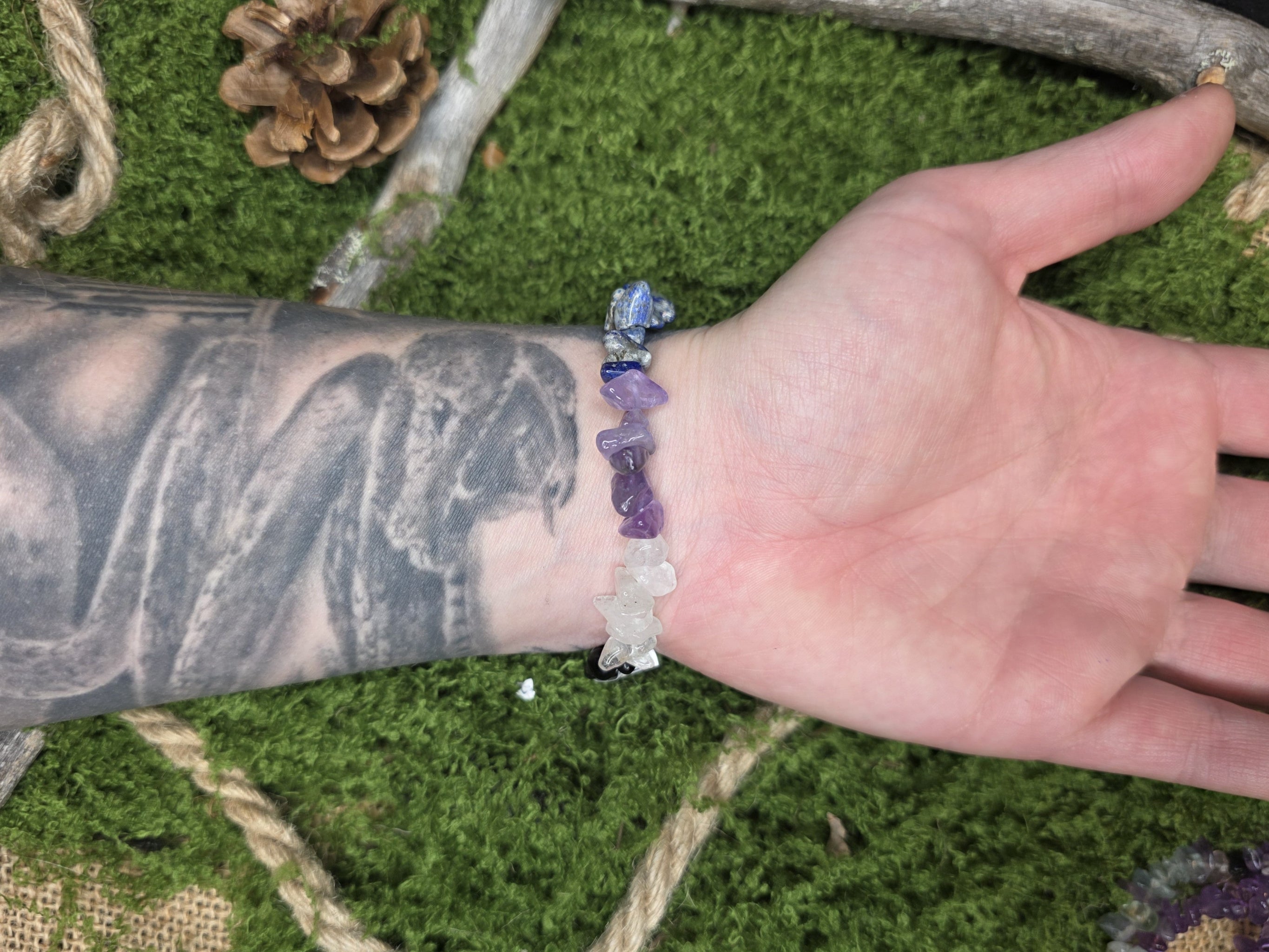 Eri värisistä kivisiruista valmistettu rannekoru mallin kädessä. 