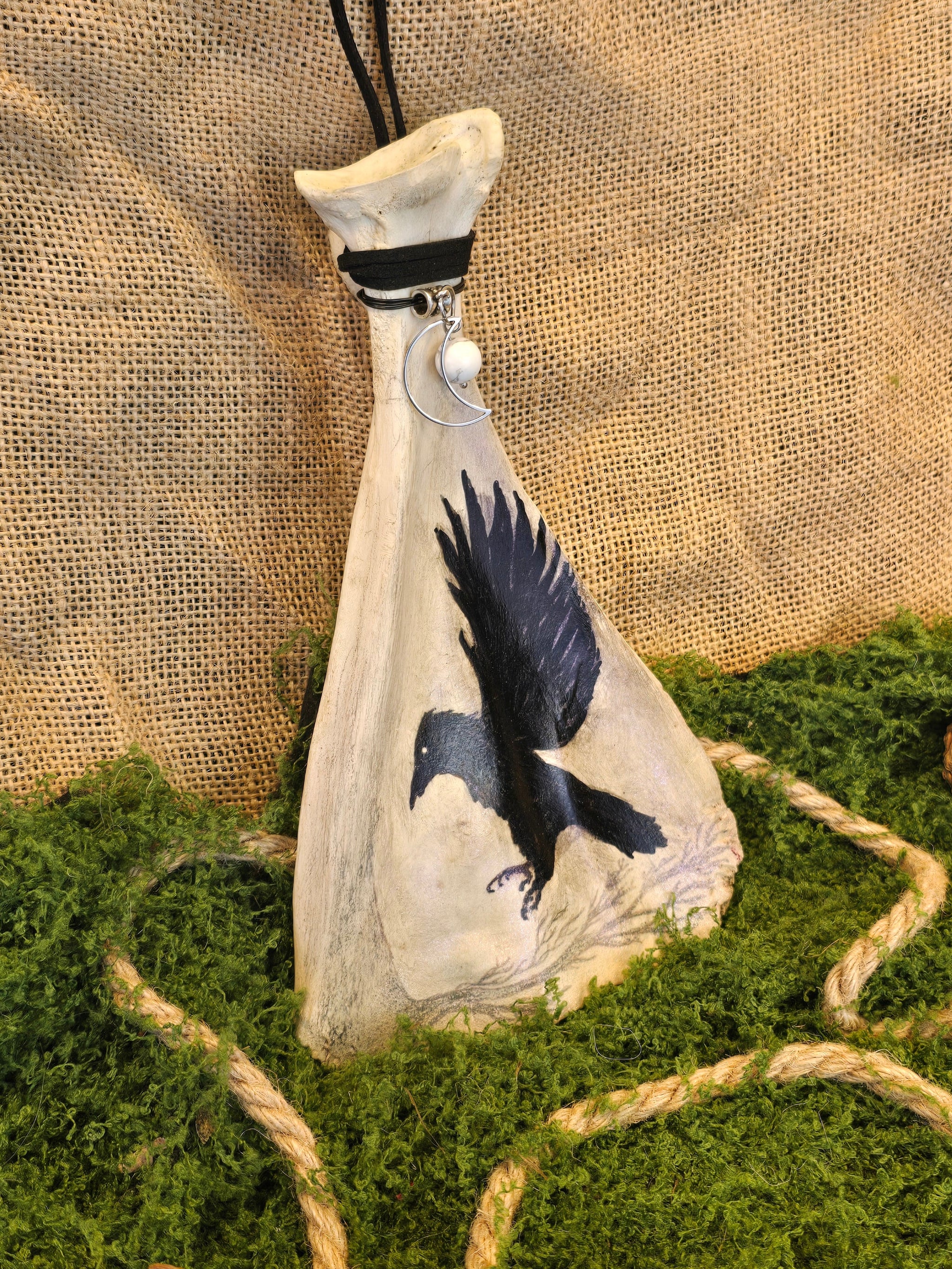 Kauriin lapaluu koriste, jossa korppimaalaus, howliittihelmi ja kuu riipus.