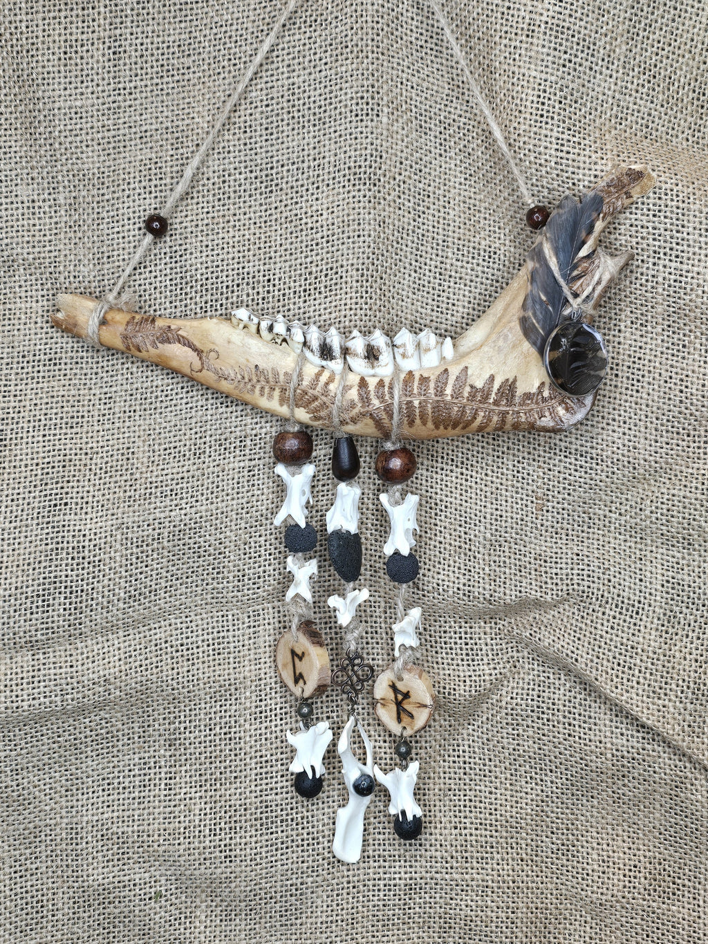 Kauriin leukaluusta, saniaisista, sulista, luusta tehty seinäkoriste. 