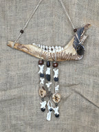 Kauriin leukaluusta, saniaisista, sulista, luusta tehty seinäkoriste. 