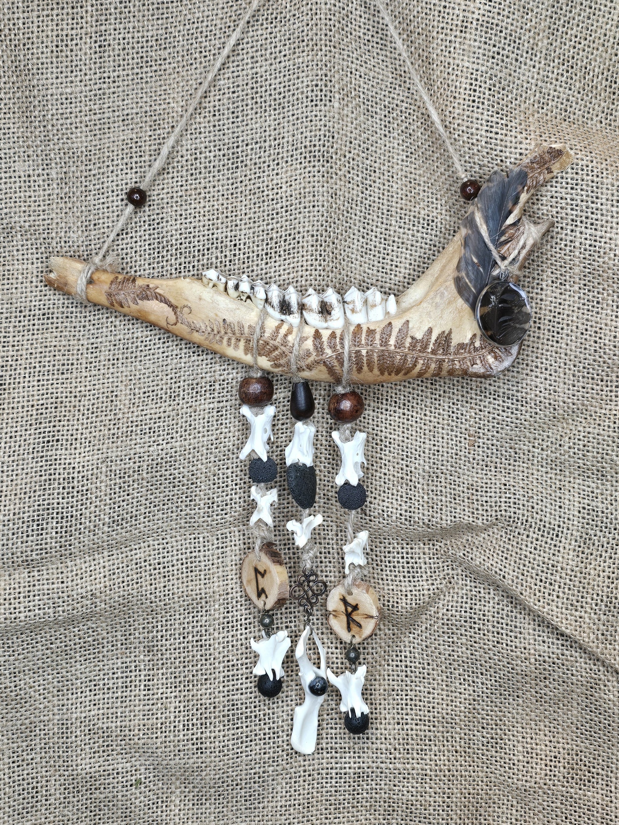 Kauriin leukaluusta, saniaisista, sulista, luusta tehty seinäkoriste. 