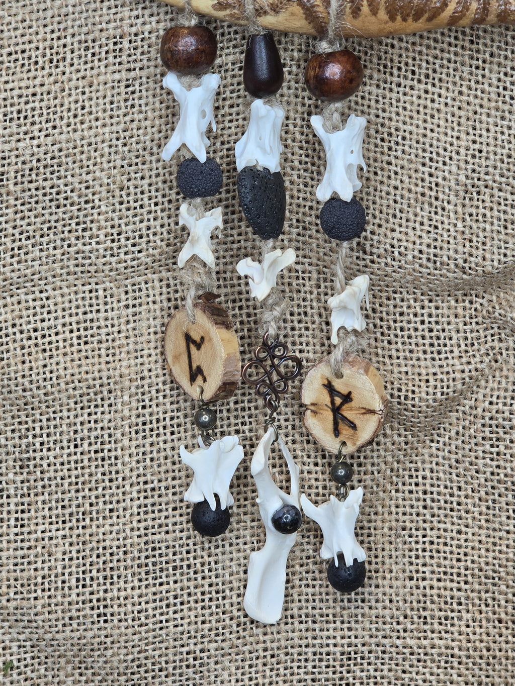 Kauriin leukaluusta, saniaisista, sulista, luusta tehty seinäkoriste. Lähikuva.