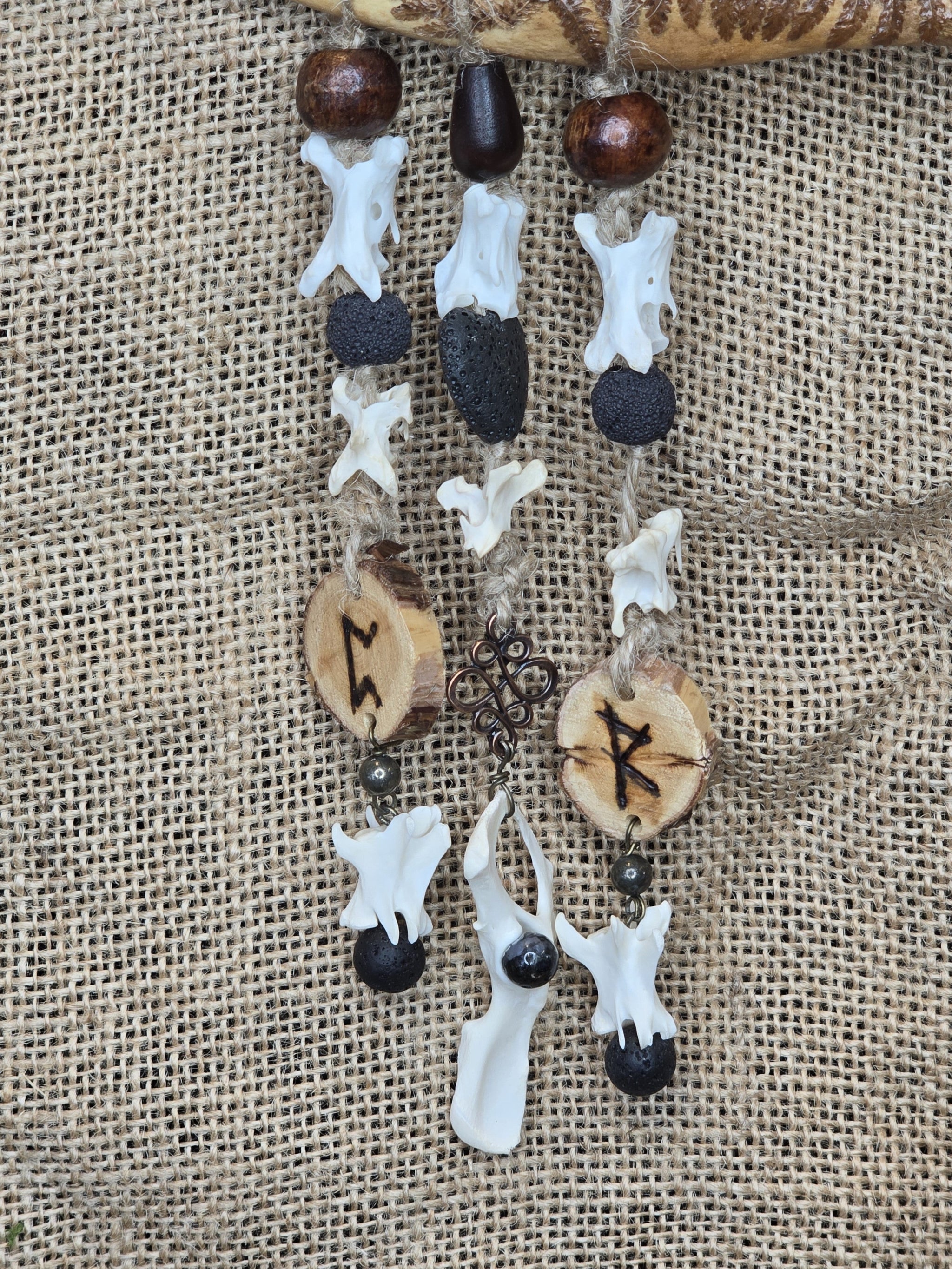 Kauriin leukaluusta, saniaisista, sulista, luusta tehty seinäkoriste. Lähikuva.