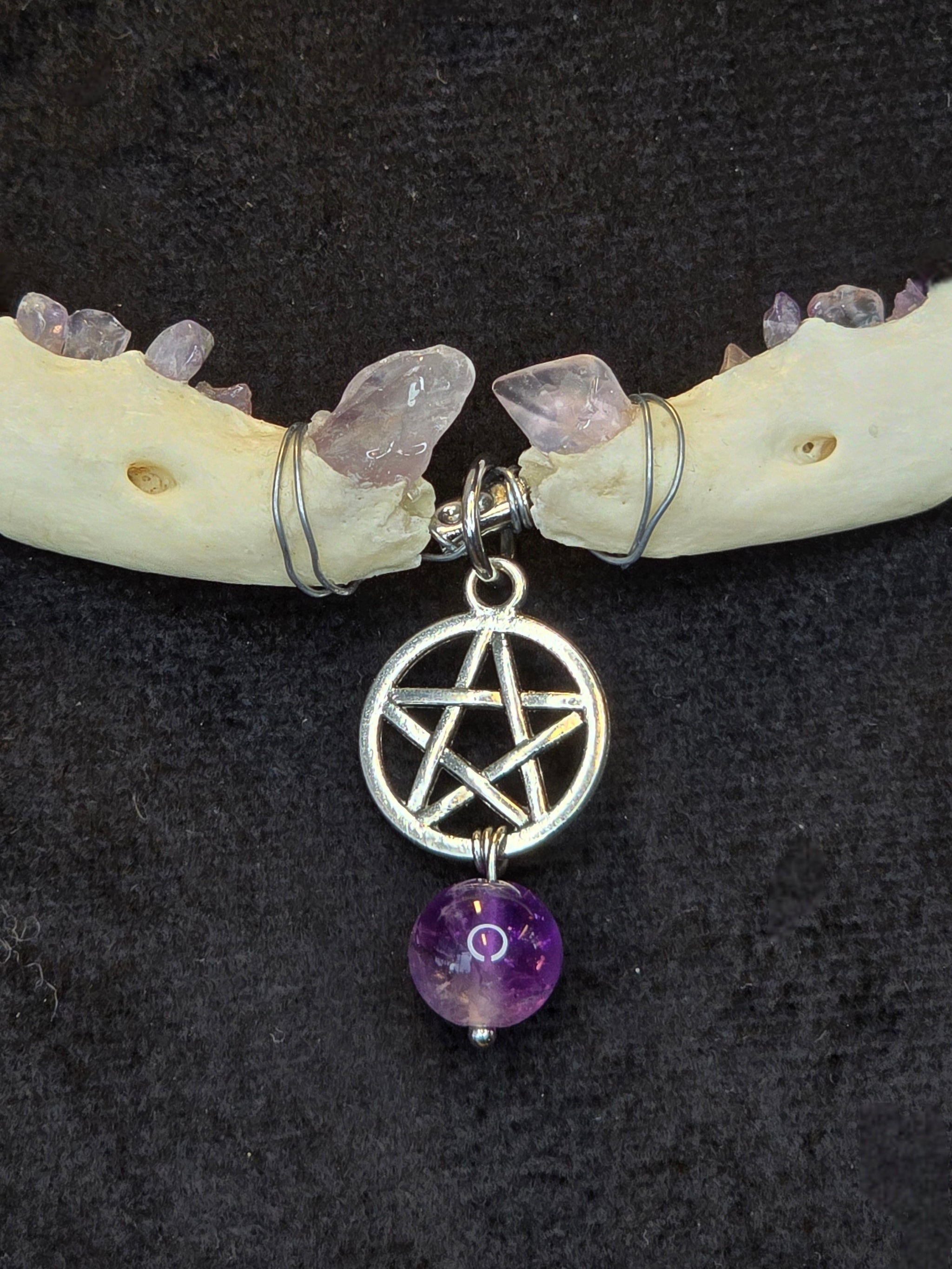 Ketun leukaluista, ametistisiruista tehty kaulakoru pentagram riipuksella. Lähikuva riipuksesta ja ametisti upotuksista.