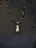 Kaulakoru, jossa lasipulloriipuksen sisällä kuningasboan luontinahkaa ja pyriittiä. Salamariipus somiste. 