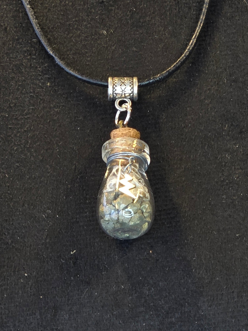 Lasipulloriipus, jonka sisällä kuningasboan luontinahka ja pyriittiä, salamariipus somiste. Amuletti.