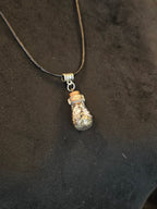 Kaulakoru, jossa lasipulloriipuksen sisällä kuningasboan luontinahkaa ja pyriittiä. Salamariipus somiste. 