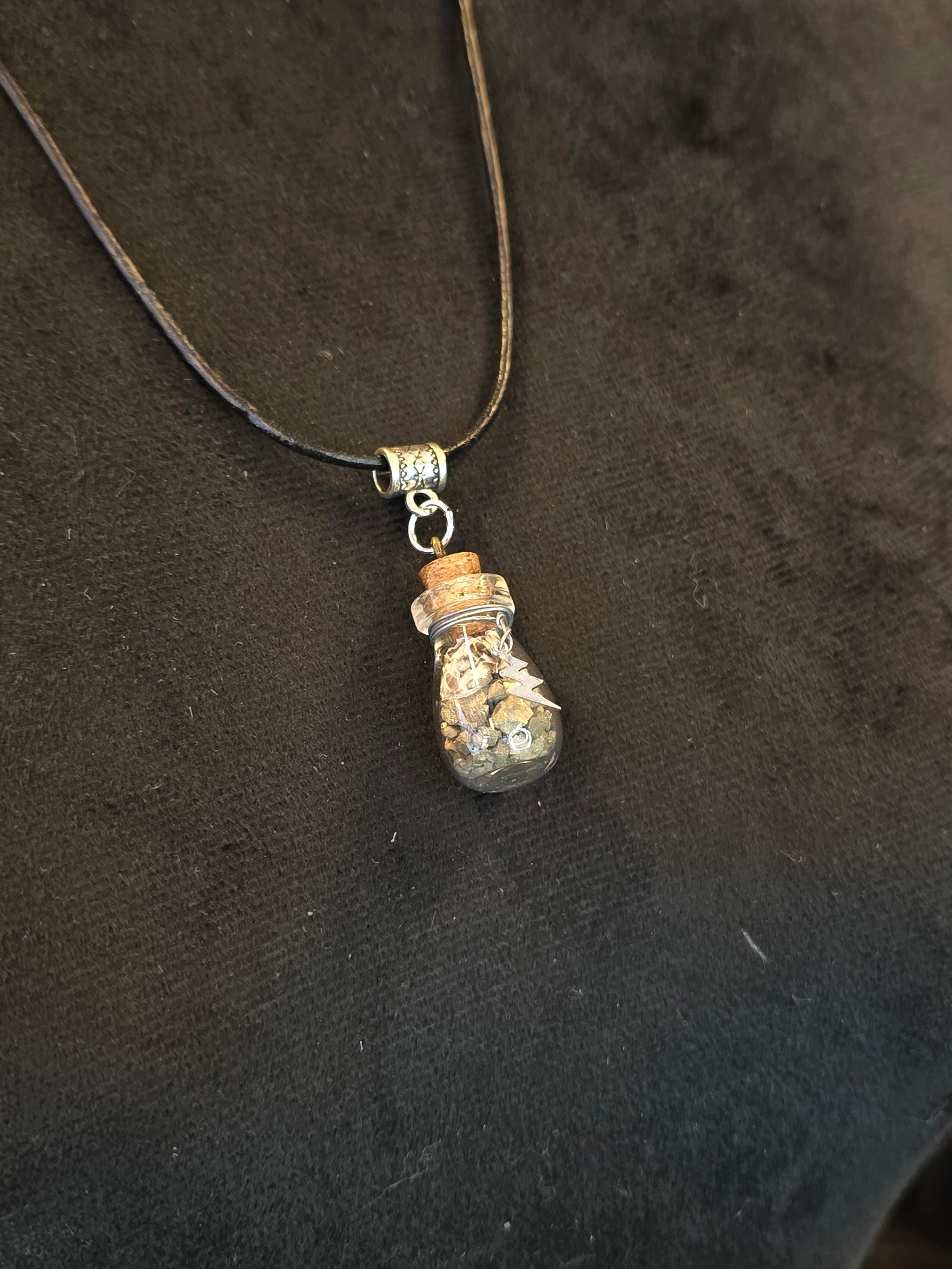 Kaulakoru, jossa lasipulloriipuksen sisällä kuningasboan luontinahkaa ja pyriittiä. Salamariipus somiste. 