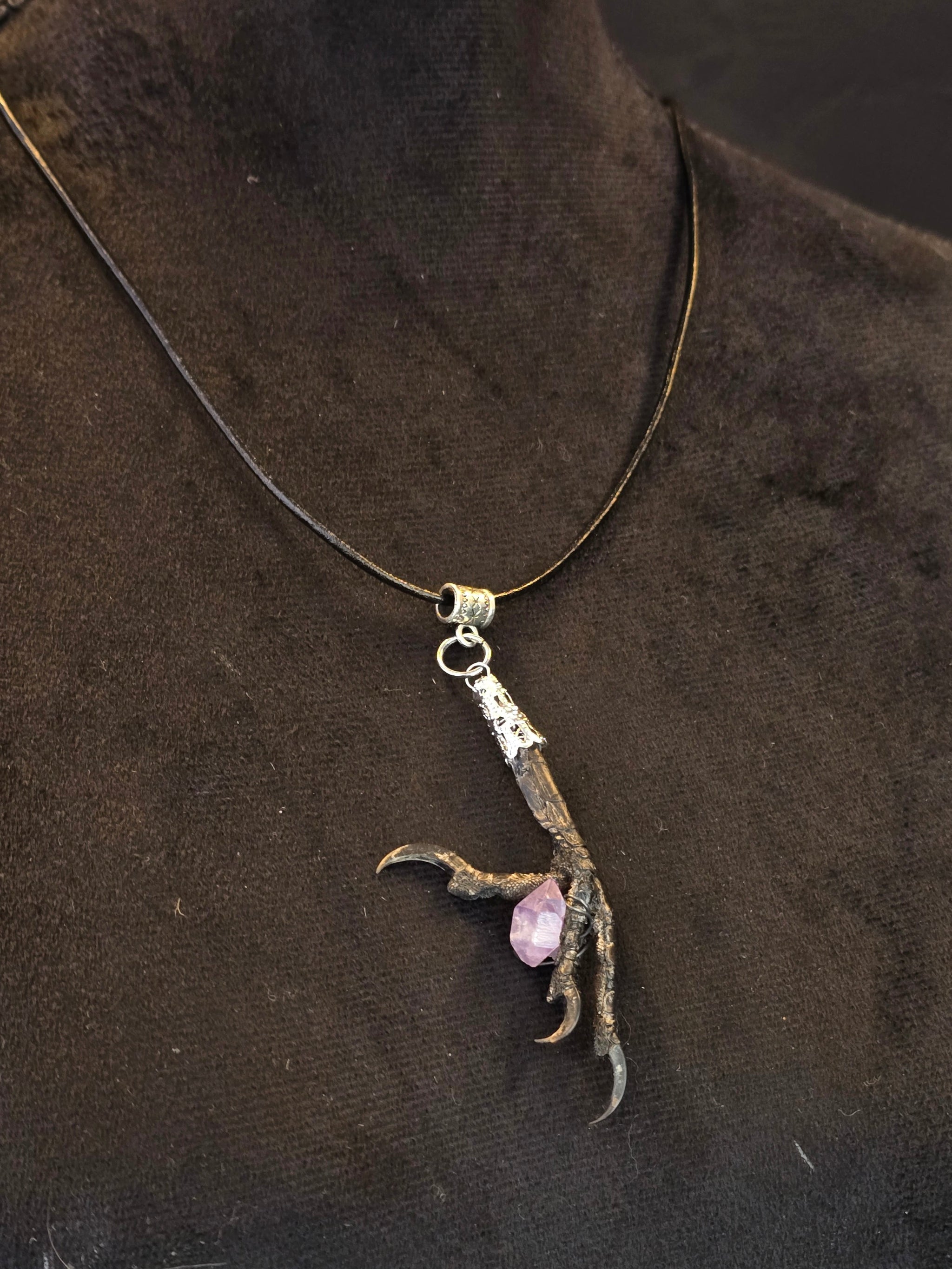 Amuletti, jossa aito naakankoipi pitelee ametistia. 