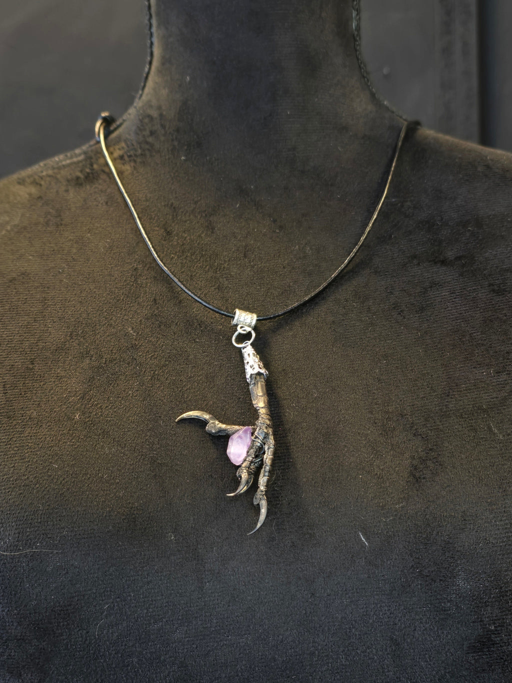 Amuletti, jossa aito naakankoipi pitelee ametistia. 