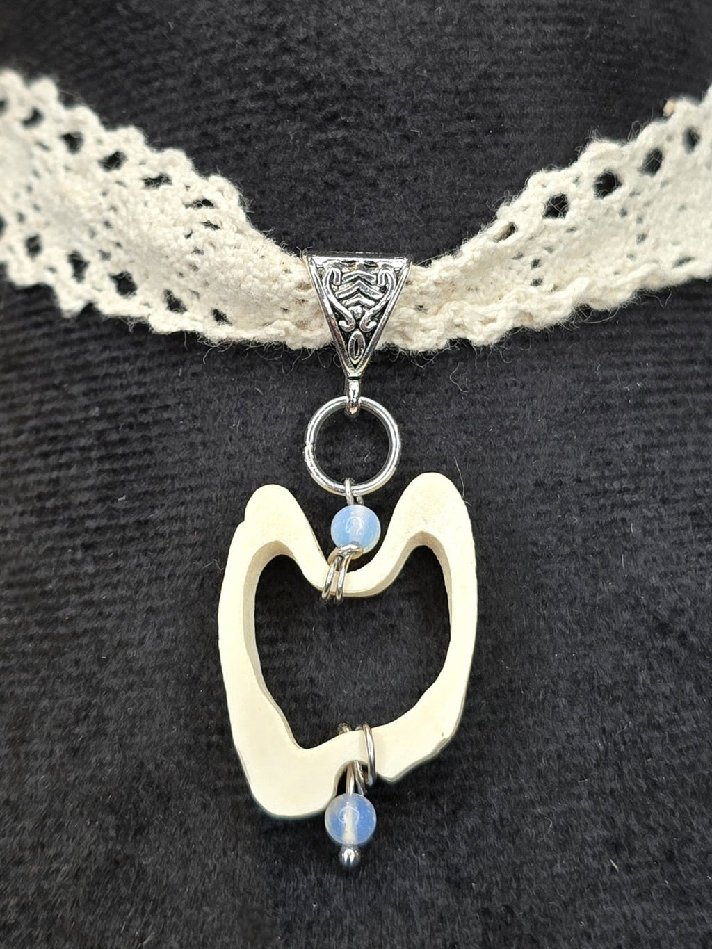 Käsityönä valmistettu pitsichoker kaulakoru, poronluu-angeliittihelmi riipuksella. Lähikuva porunluisesta riipuksesta. Inked Mystiqs verkkokaupasta. Kuunjuurella valmistama.