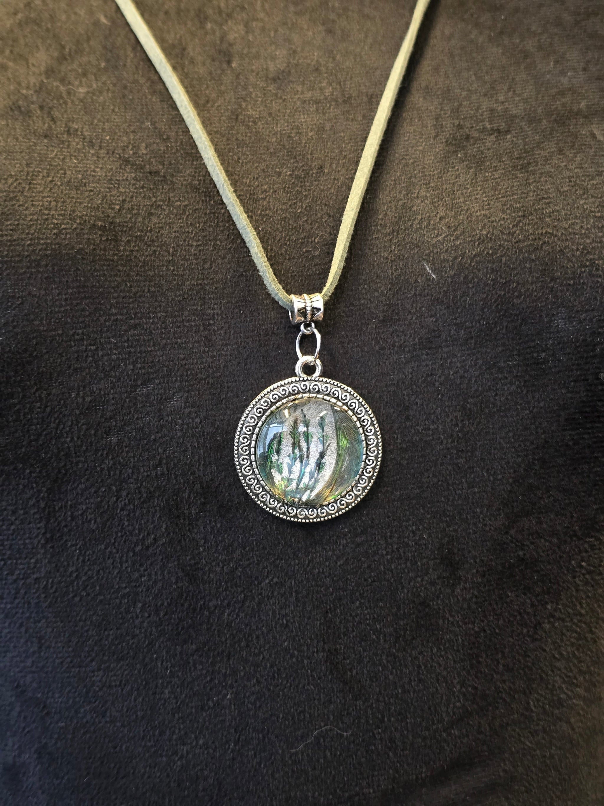 Kaulakoru, jossa lasiriipuksessa riikinkukonsulkaa. 