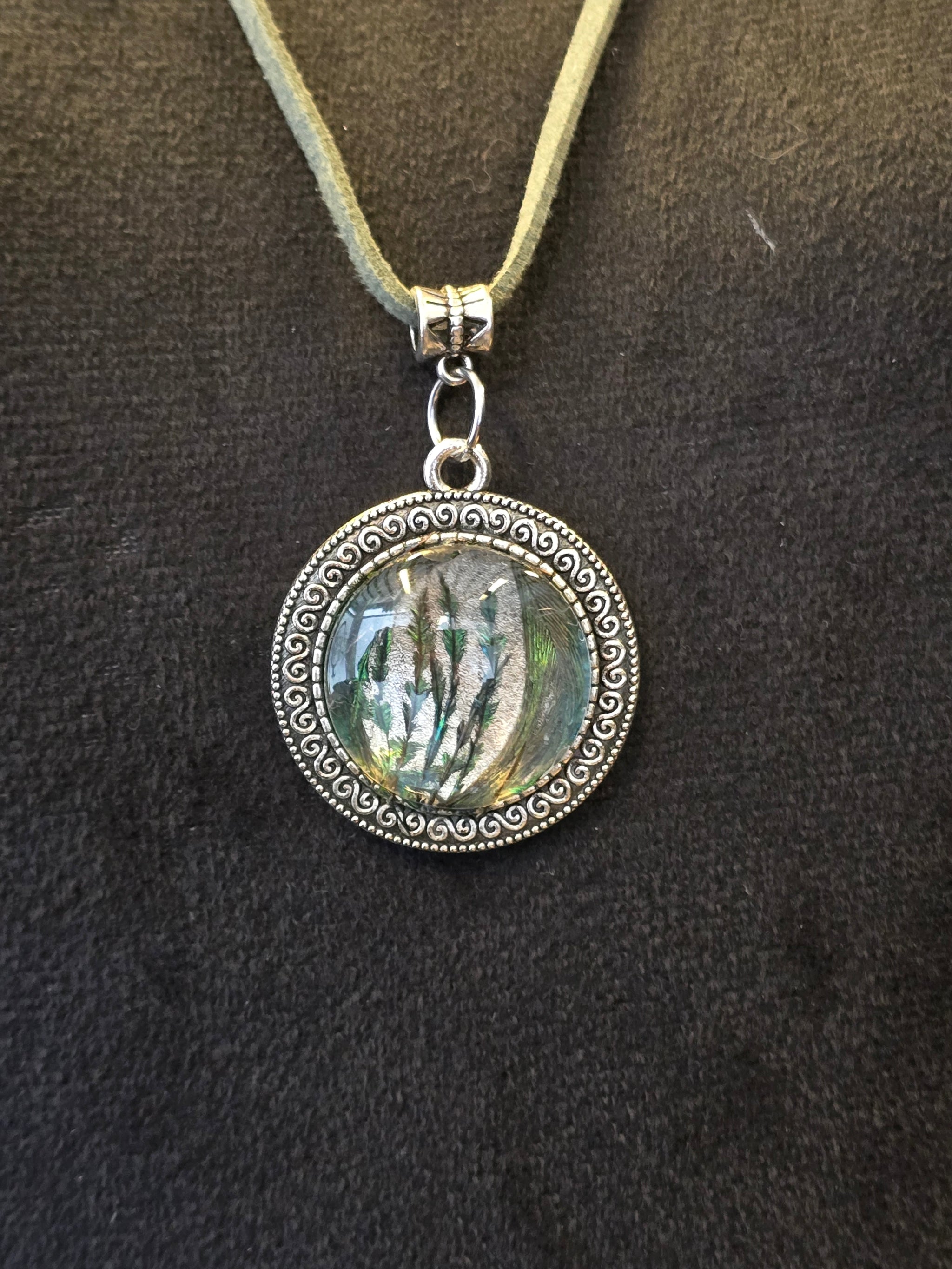 Kaulakoru, jossa lasiriipuksessa riikinkukonsulkaa. 