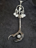 Kaulakoru, jossa variksen jalka, naakan nikamaluu. Koristeltu myös seleniitti ja kuukivihelmillä. Lähikuva.