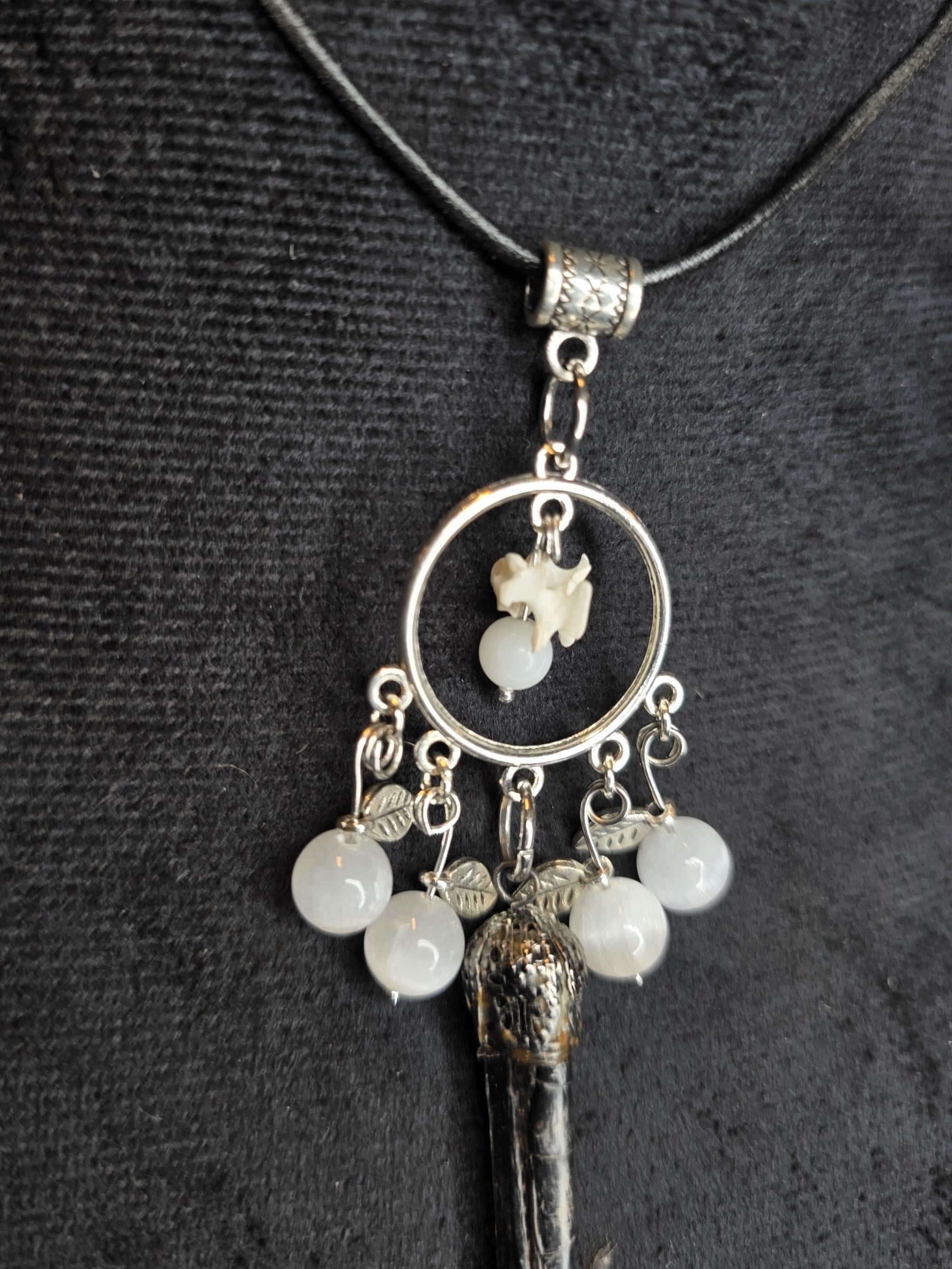 Kaulakoru, jossa variksen jalka, naakan nikamaluu. Koristeltu myös seleniitti ja kuukivihelmillä. Lähikuva yksityiskohdasta.