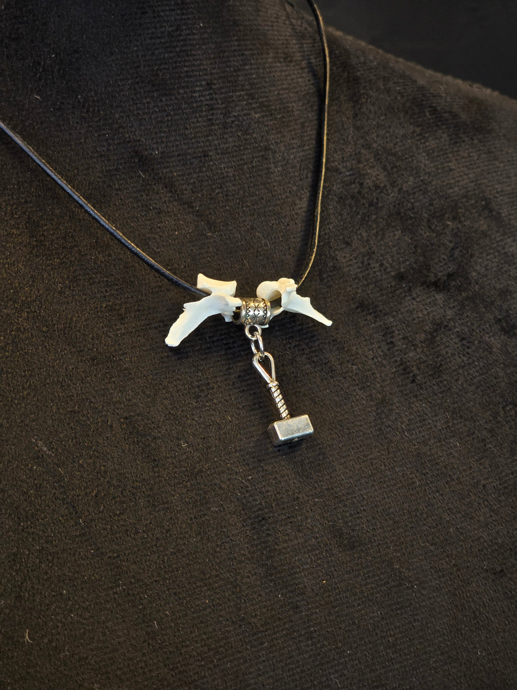 Kaulakoru, jossa thorin vasara symboli ja variksen nikamat. 