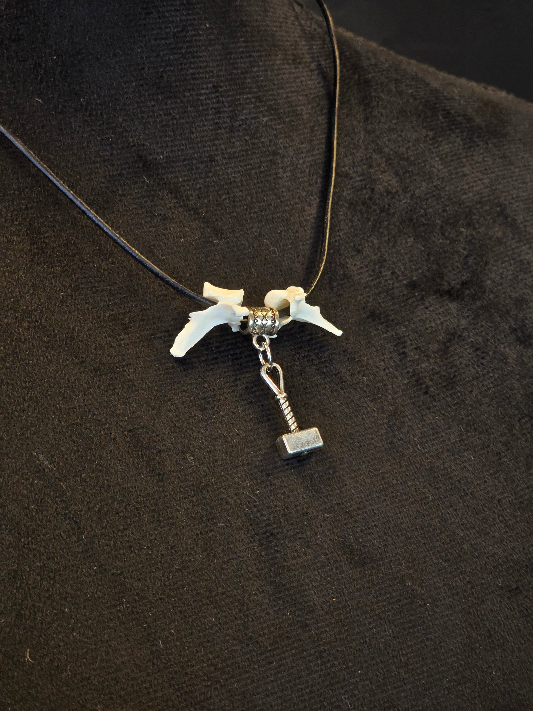 Kaulakoru, jossa thorin vasara symboli ja variksen nikamat. 