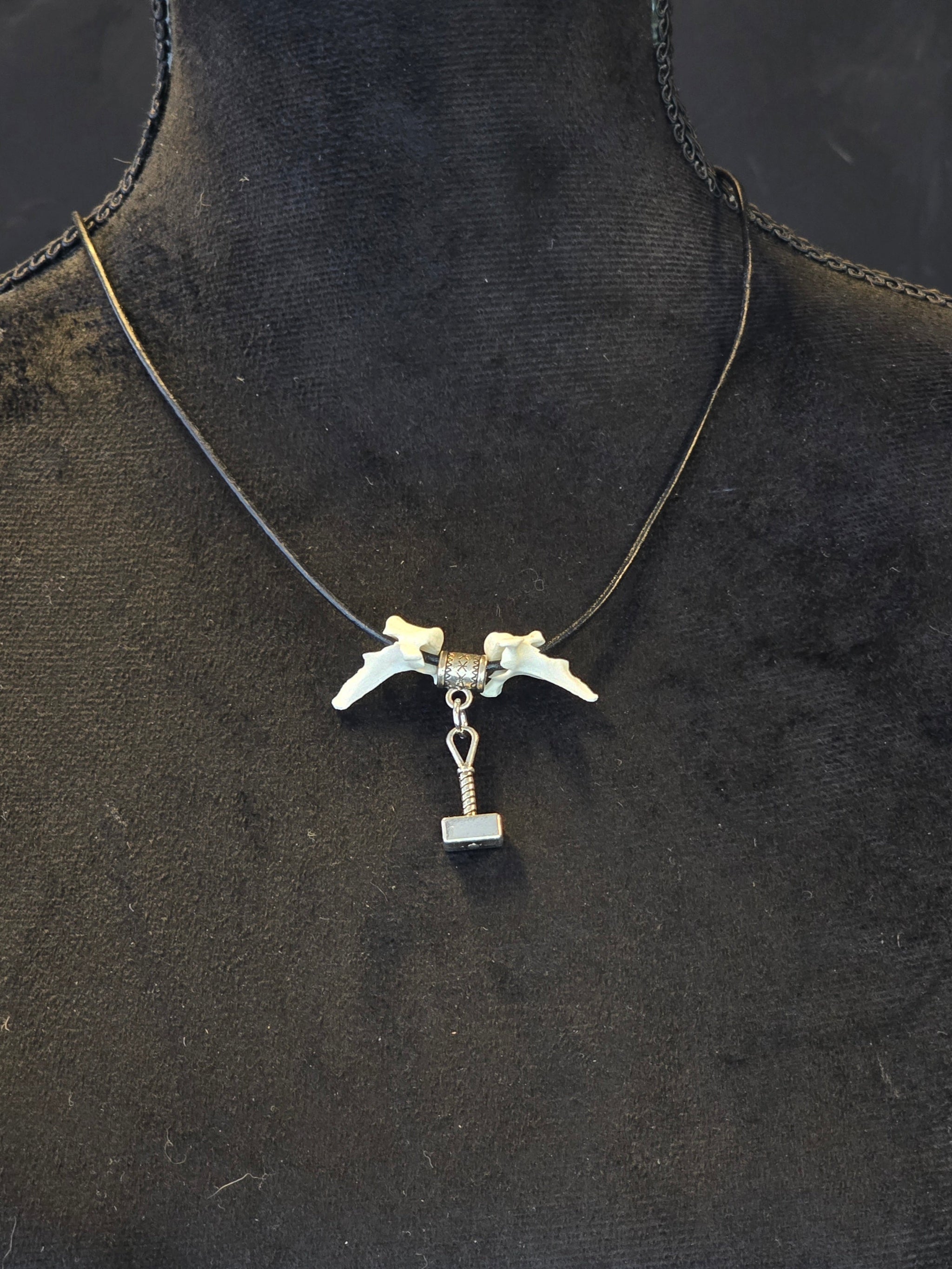 Kaulakoru, jossa thorin vasara symboli ja variksen nikamat. 