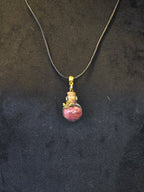 Kaulakoru, jossa lasipulloriipuksen sisällä ruusunterälehtiä ja rodoniittikivi, somisteena pieni yöperhonen riipus. 