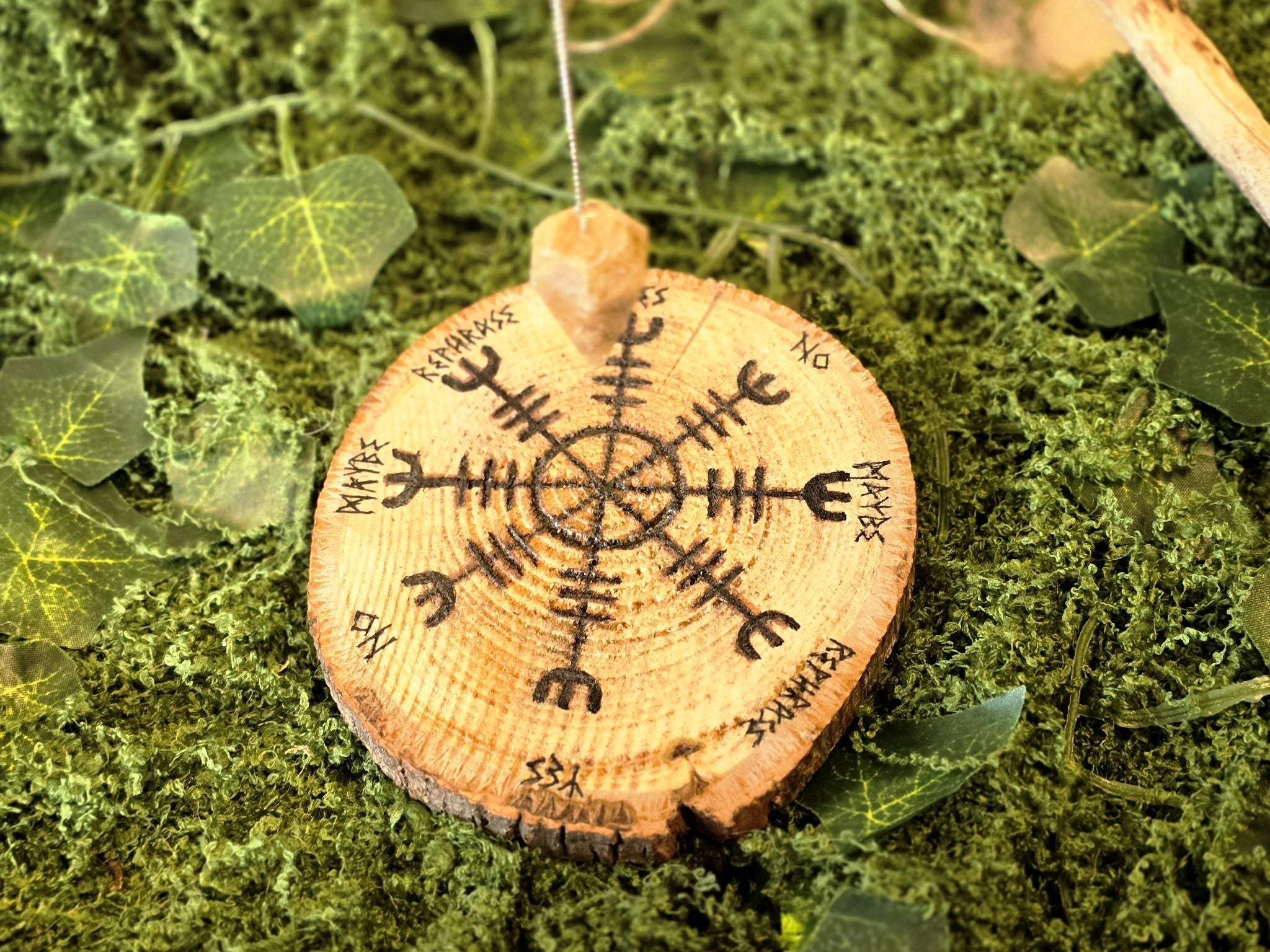 Puukiekosta valmistettu heilurialusta, jossa Vegvísir symboli.