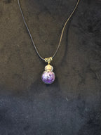 Lasipulloriipus, jonka sisällä ametistisiruja.