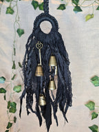 Musta noitakello, jossa roikkuu kultaisen värisiä kelloja ja avain.