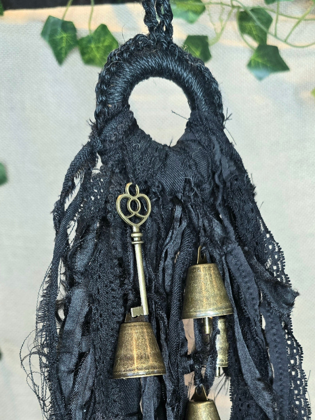 Musta noitakello, jossa roikkuu kultaisen värisiä kelloja ja avain.