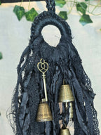 Musta noitakello, jossa roikkuu kultaisen värisiä kelloja ja avain.