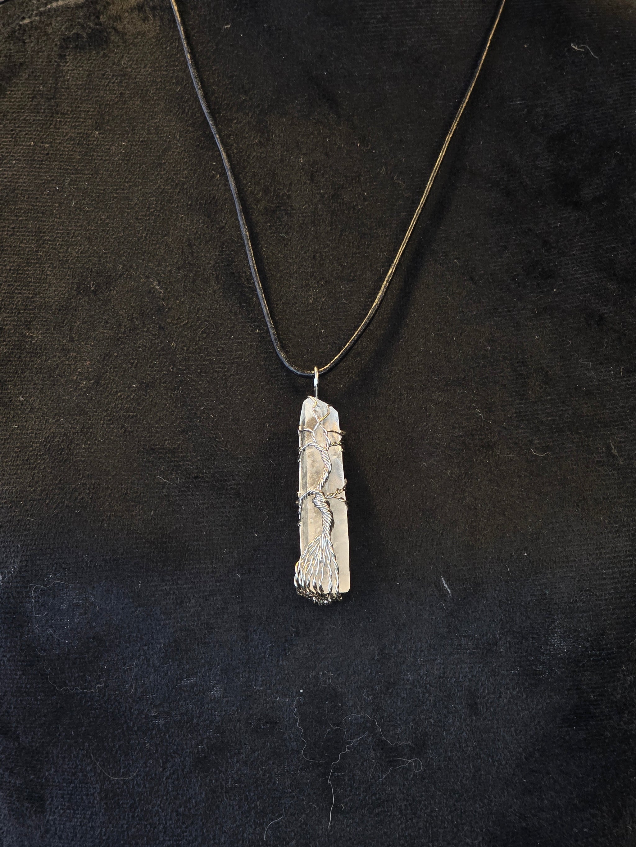 Vuorikristalli, johon on kuvioitu hopealangalla elämänpuusymboli. Kaulakoru. 