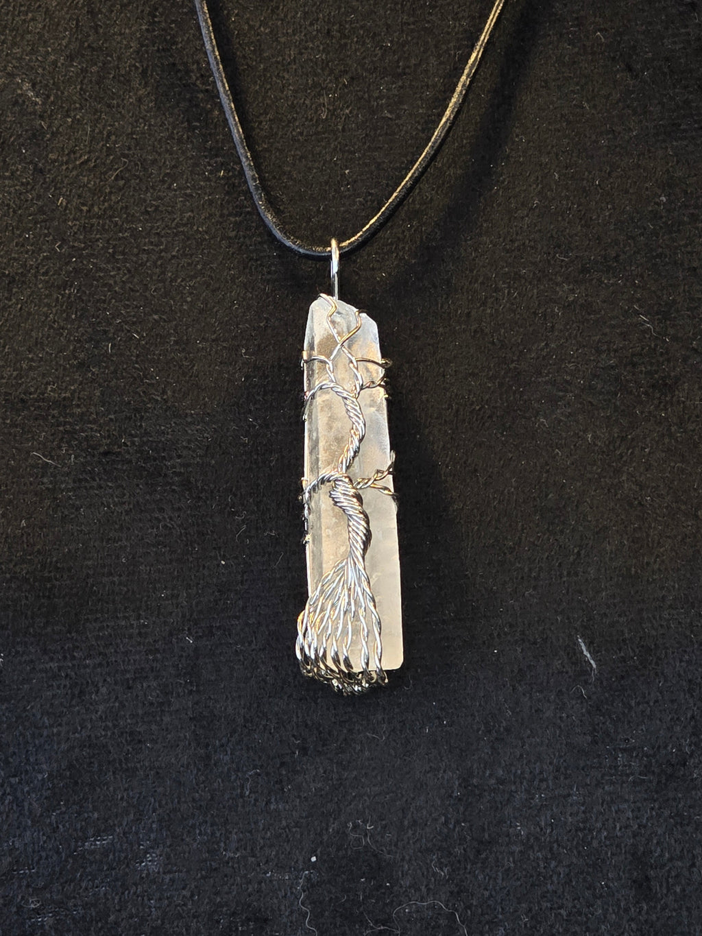 Vuorikristalli kaulakoru, jossa kuvioitu elämänpuusymboli hopalangalla.