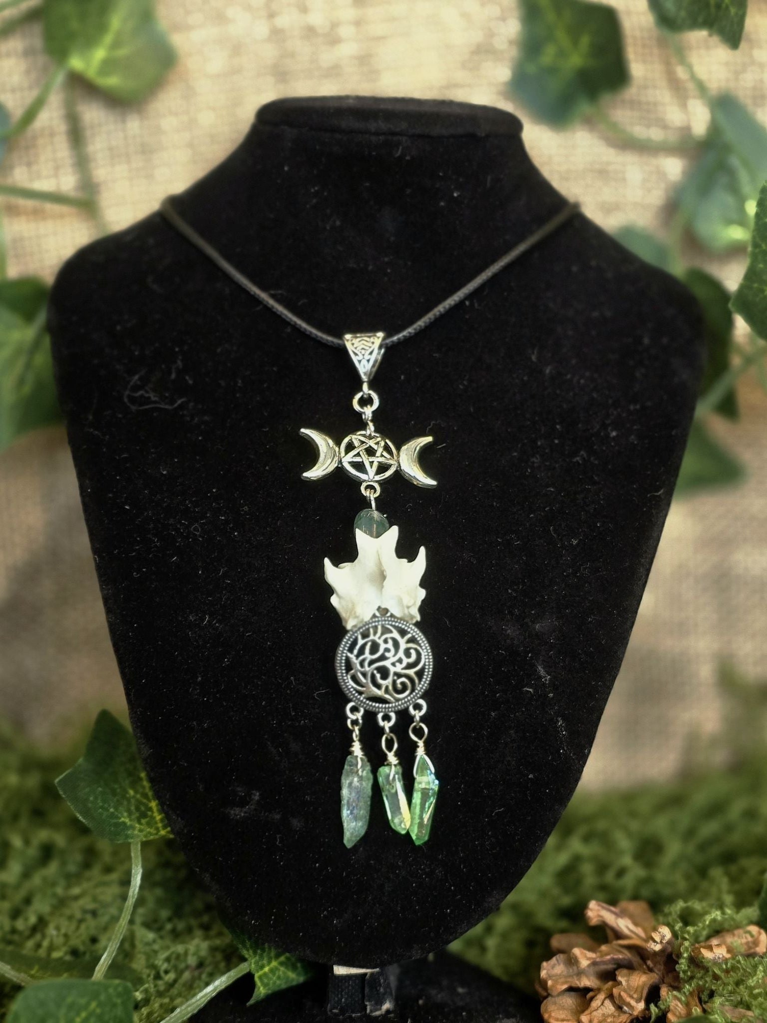 Upea uniikki kaulakoru, jossa triple moon symboli, sammalakaatti, ketunnikama, pyöreä amuletti, josta roikkuu vihreä hohtoisia värjättyjä kvartsikiviä.