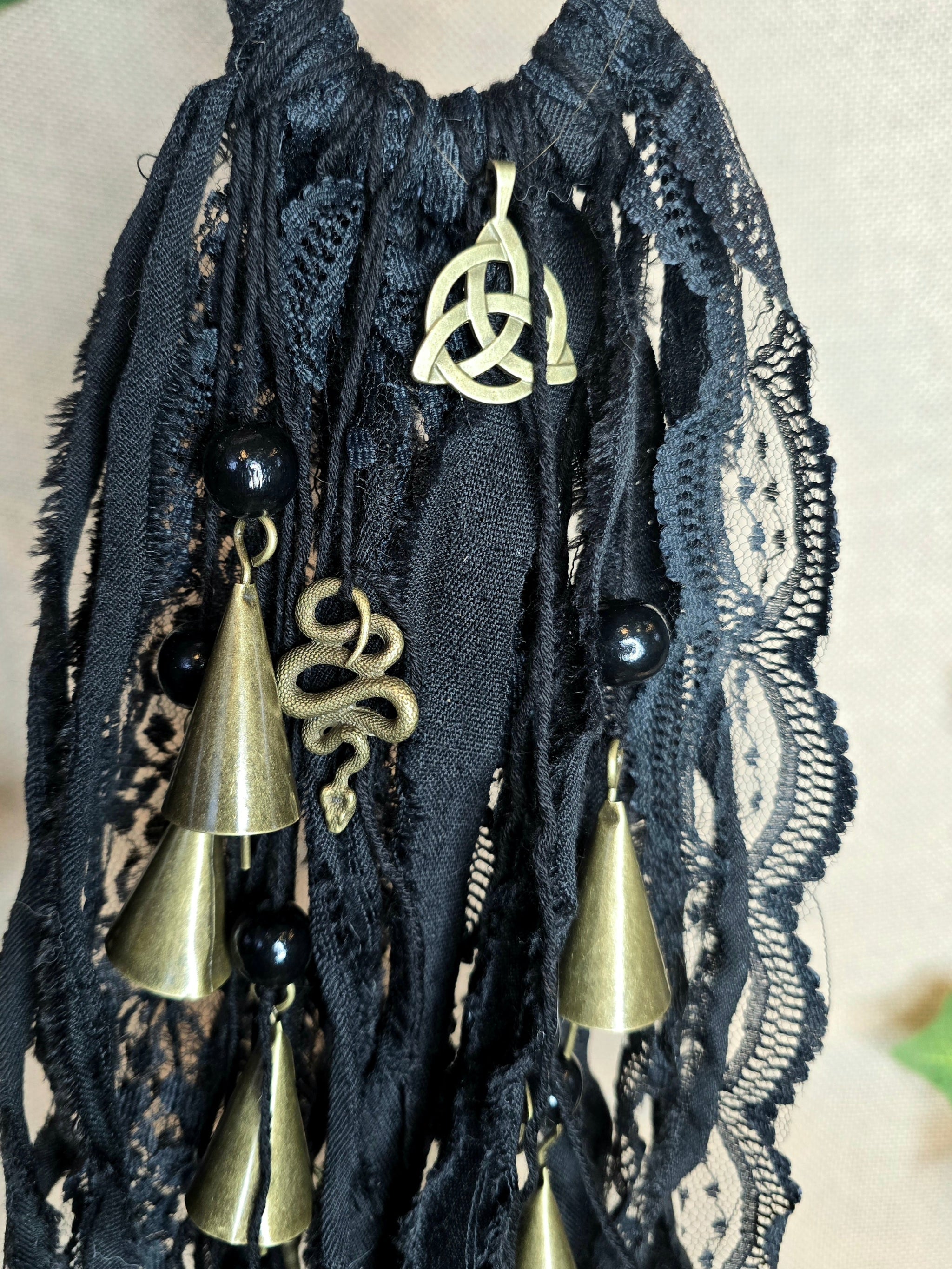 Musta noitakello, jossa kullanväristen kellojen lisäksi käärme ja triquetra symbolit.