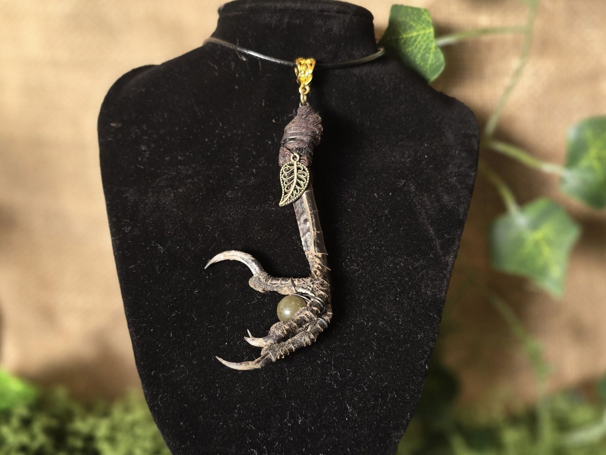 Uniikki kaulakoru, jossa korpinjalka pitelee labradoriitti helmeä.