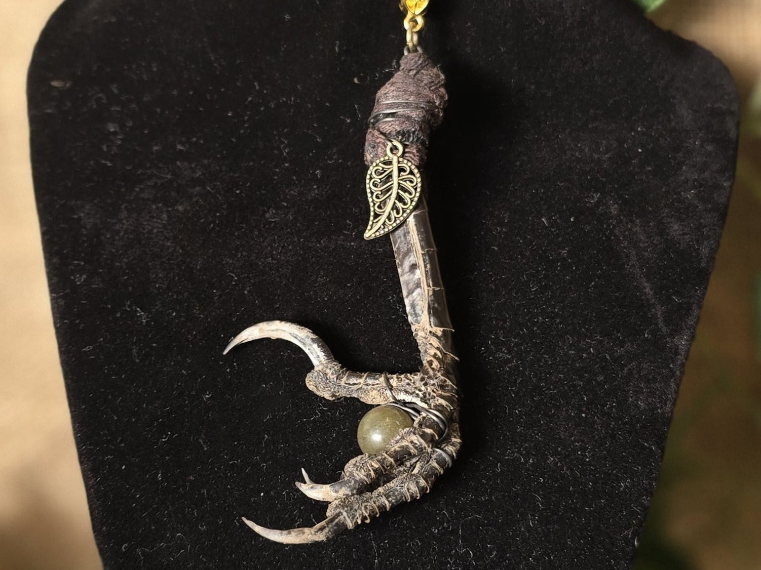 Uniikki kaulakoru, jossa korpinjalka pitelee labradoriitti helmeä.