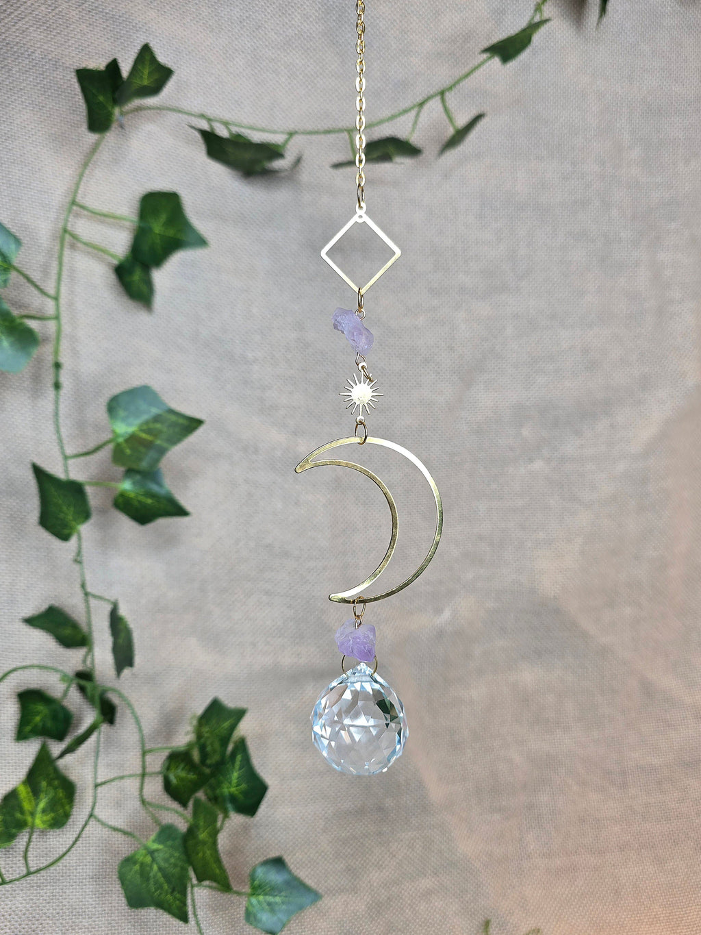 Kuunvalo aurinkosieppari, jossa lasikristalli, iso kuu somiste ja pienempi aurinko somiste.