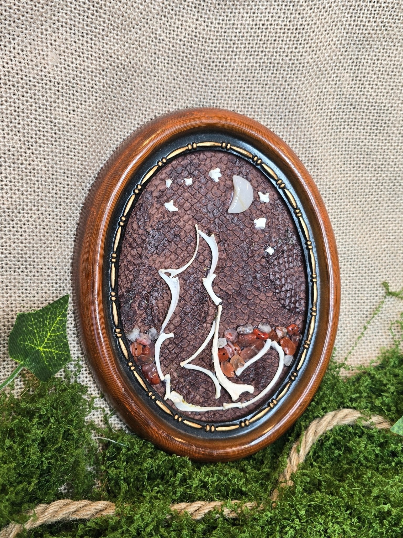 Taulu, jonka taustalla käytetty käsiteltyä lohen nahkaa. Näädän ja kissan luista muotoiltu susi, karneolia maana, kuun ja täden muodostava kuukivi ja lumikvartsi.