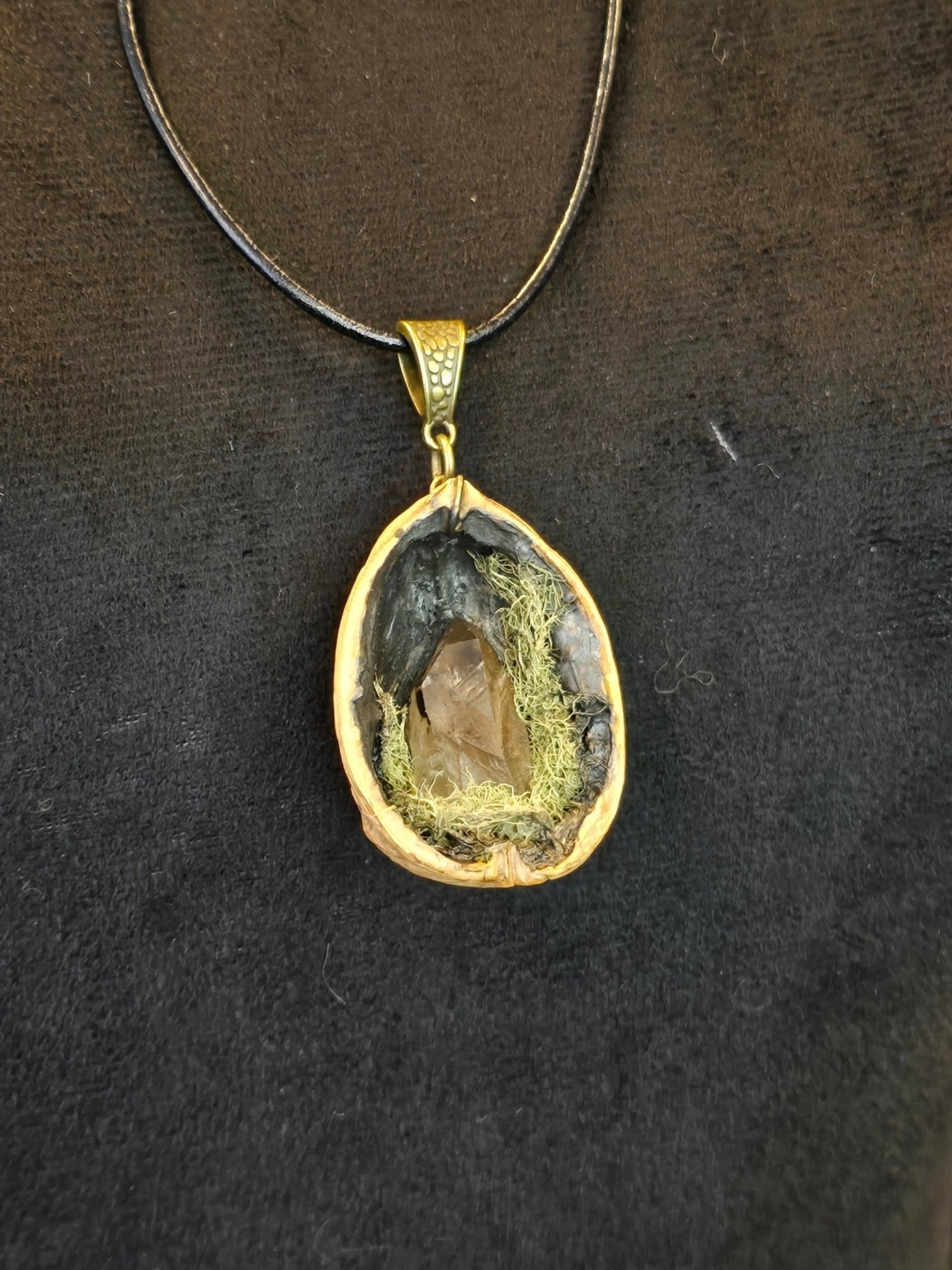 Saksanpähkinän kuoresta tehty amuletti, jossa sammalta ja savukvartsi. Metsän oma salaisuus.