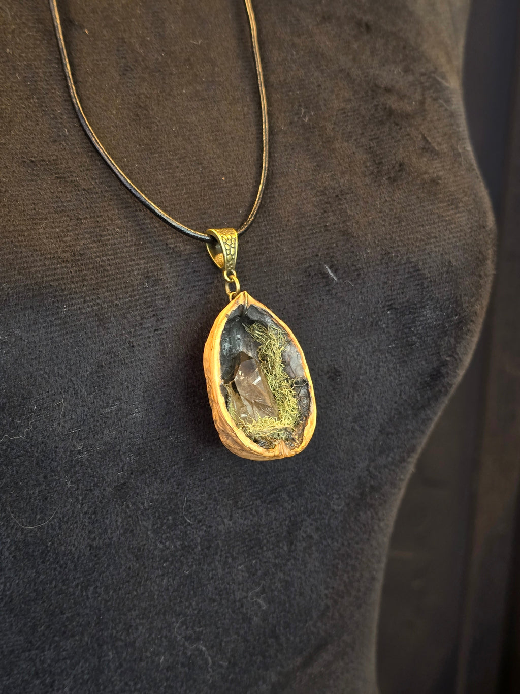 Saksanpähkinän kuoresta tehty amuletti, jossa sammalta ja savukvartsi. Metsän oma salaisuus.