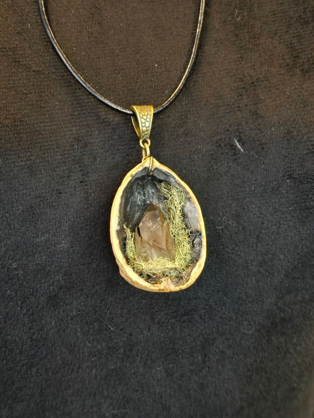 Saksanpähkinän kuoresta tehty amuletti, jossa sammalta ja savukvartsi. Metsän oma salaisuus.