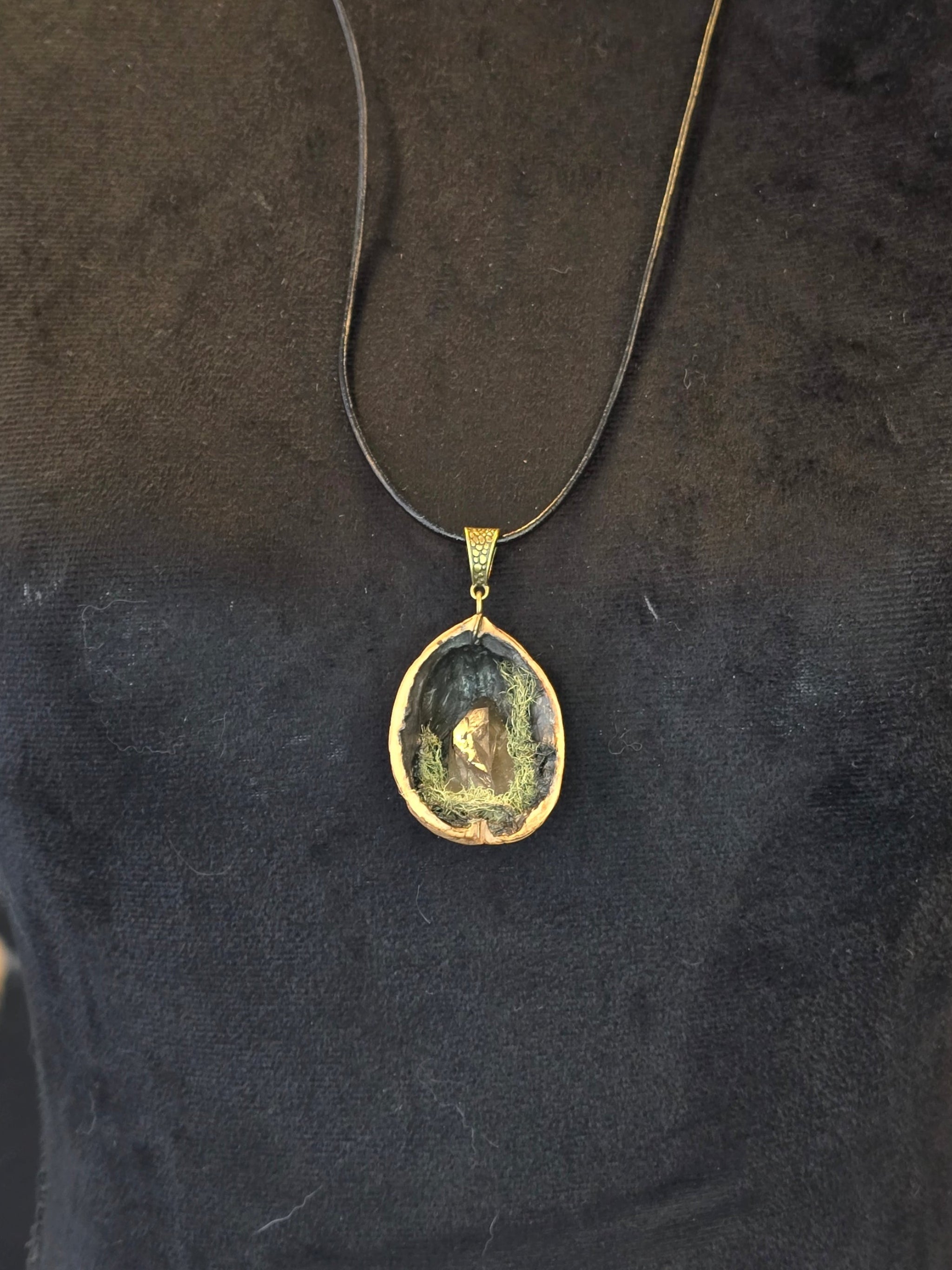 Saksanpähkinän kuoresta tehty amuletti, jossa sammalta ja savukvartsi. Metsän oma salaisuus.