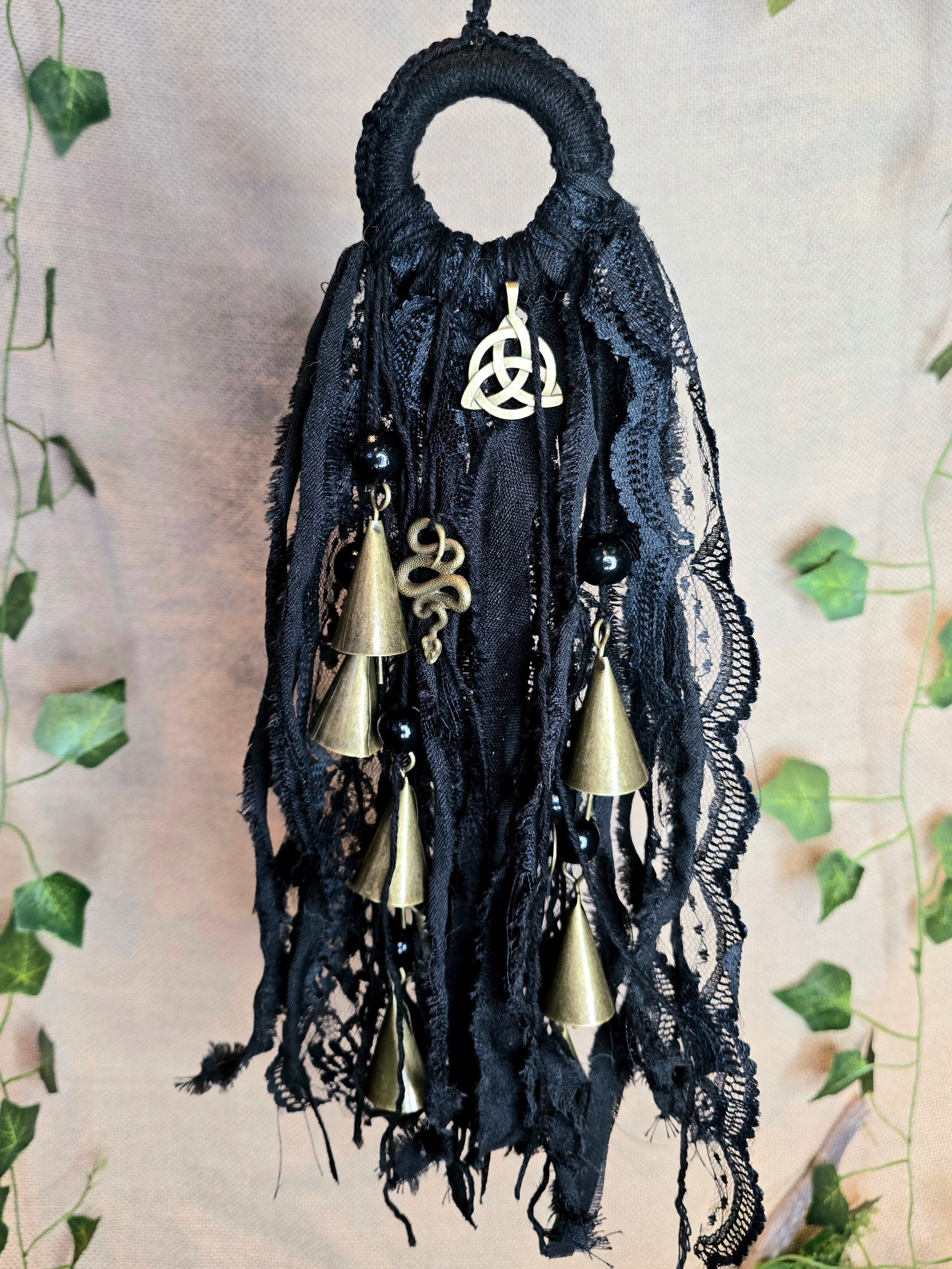 Musta noitakello, jossa kullanväristen kellojen lisäksi käärme ja triquetra symbolit.