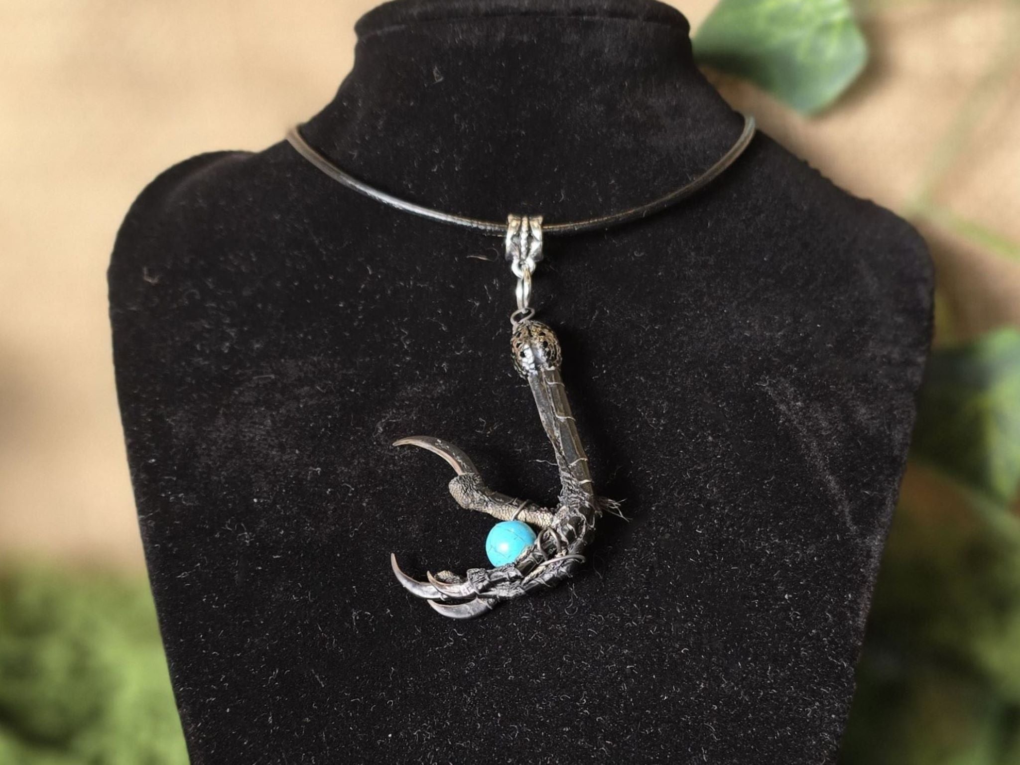 Kaulakoru, jossa naakankoipi pitelee turkoosia howliitti helmeä. 