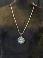 Kaulakoru, jossa lasiriipuksessa riikinkukonsulkaa. 