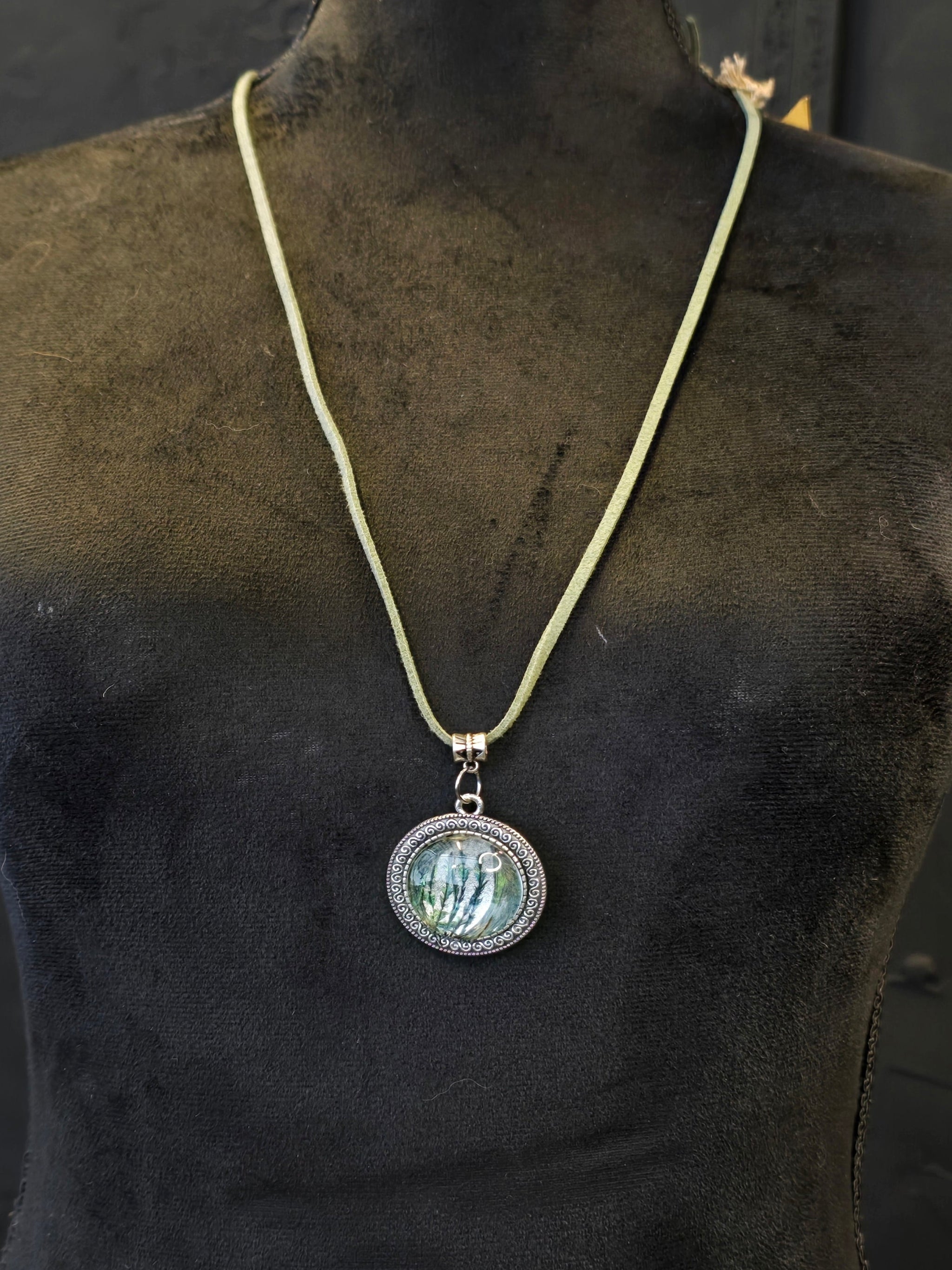 Kaulakoru, jossa lasiriipuksessa riikinkukonsulkaa. 