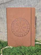 Ruskea muistikirja vegvisir symbolilla ja kynällä edestä.