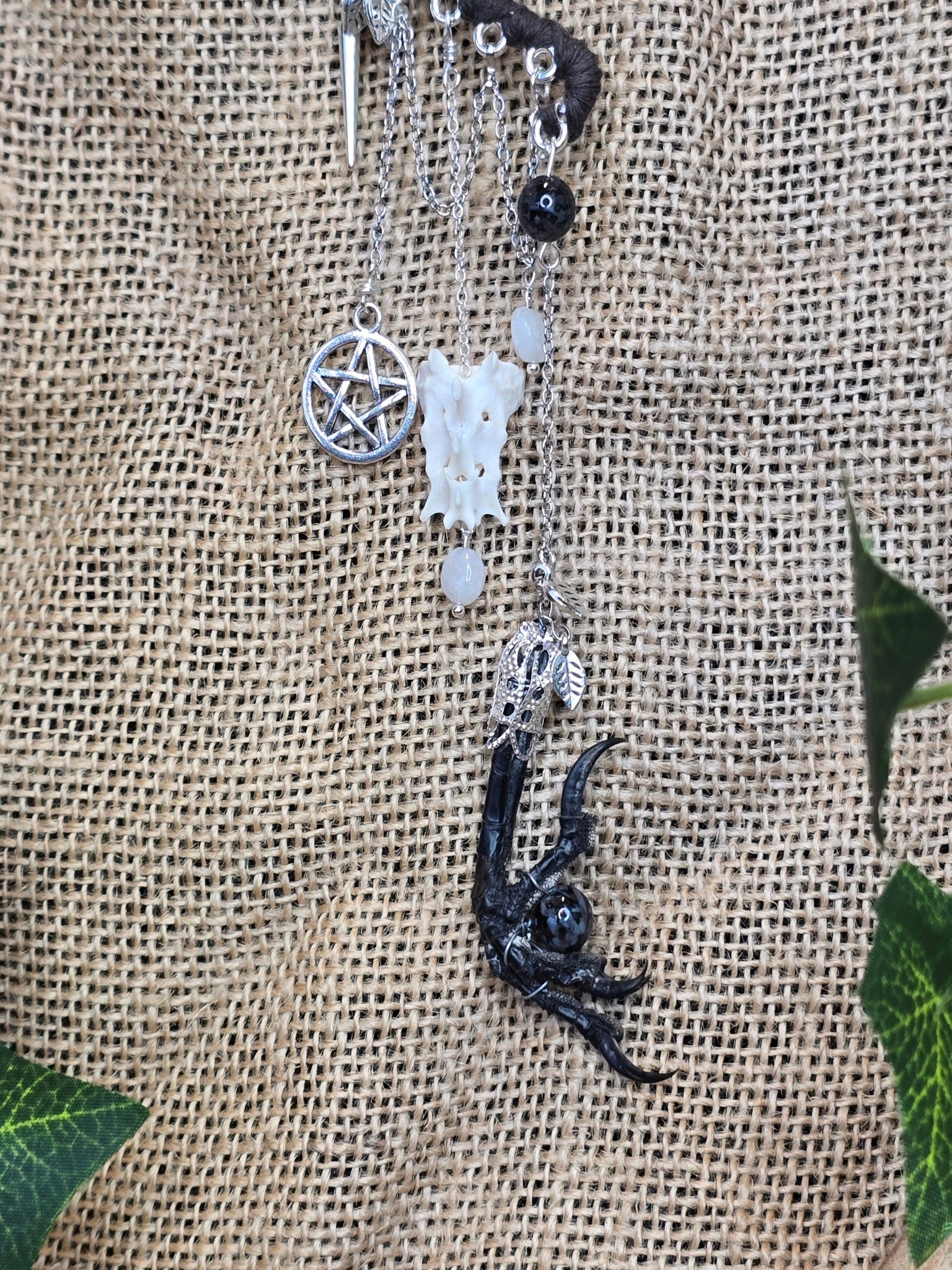 Tumma korvakääty, jossa pentagram riipus, rotanluu, kuukivihelmet, naakan koipi ja astrofyllittihelmet. 