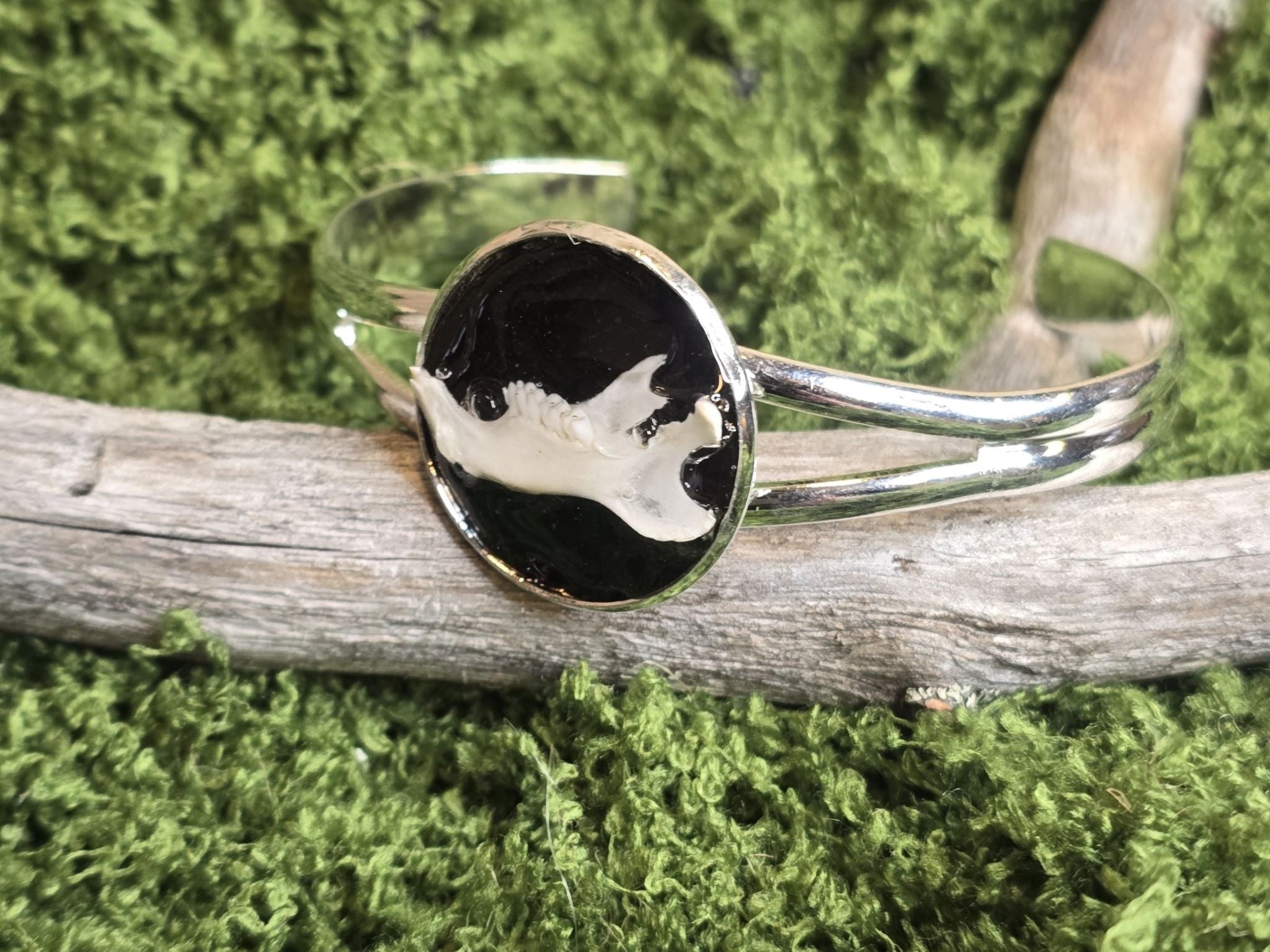 Säädettävä rannekoru, jossa on rotan leukaluu mustaksi värjättyä lohennahkaa vasten. 