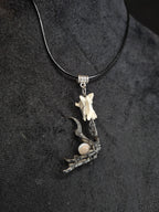 Kaulakoru, jossa naakan jalka pitelee kuukivihelmeä. Koristettu myös supikoiran nikamaluulla. Lähikuva.