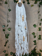 Valkoinen noitakello, jossa puuhelmiä, hopeisia kelloja, pentagram riipus ja kuukivi.